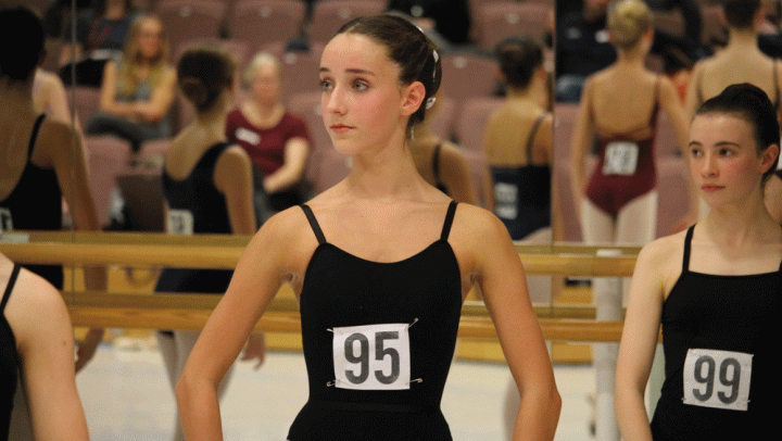 Student in a black leotard wearing a black and white audition number